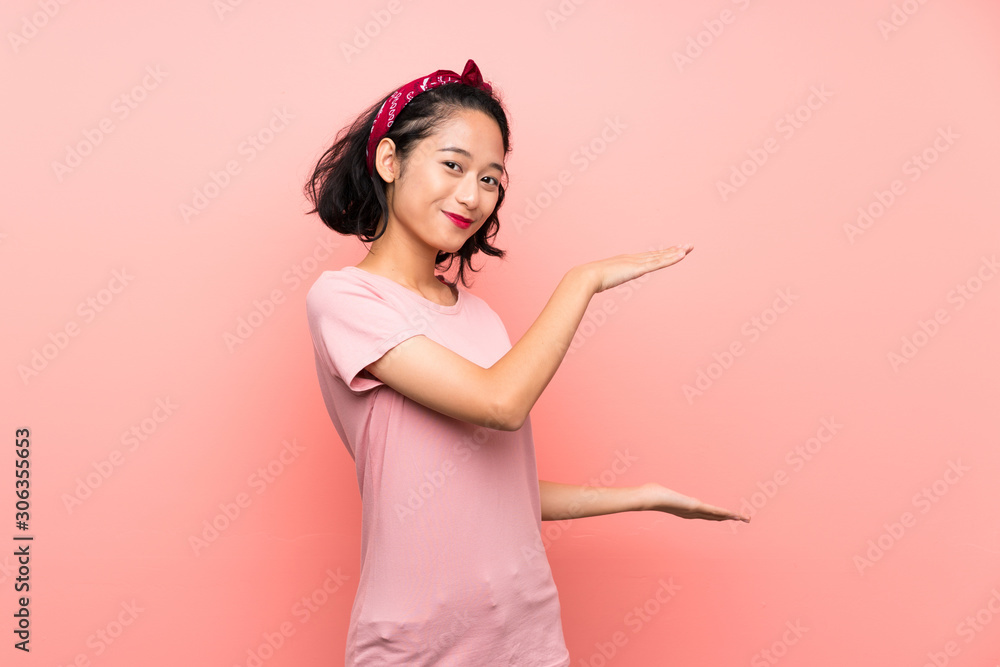Asian young woman over isolated pink background holding copyspace to insert an ad Asian young woman over isolated pink background holding copyspace to insert an ad