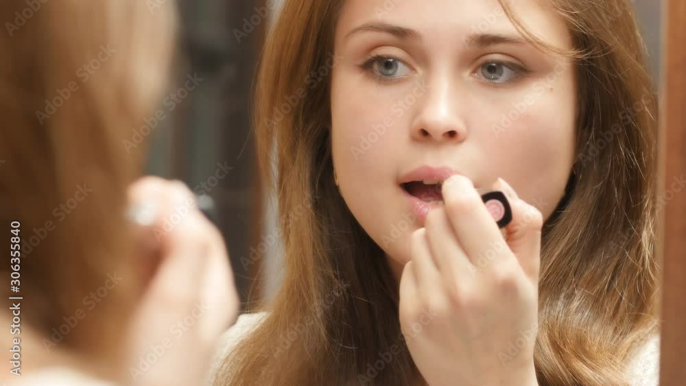 girl paints her lips with lipstick in front of a mirror at home, a young woman doing makeup, a concept of female natural beauty and cosmetics girl paints her lips with lipstick in front of a mirror at home, a young woman doing makeup, a concept of female natural beauty and cosmetics