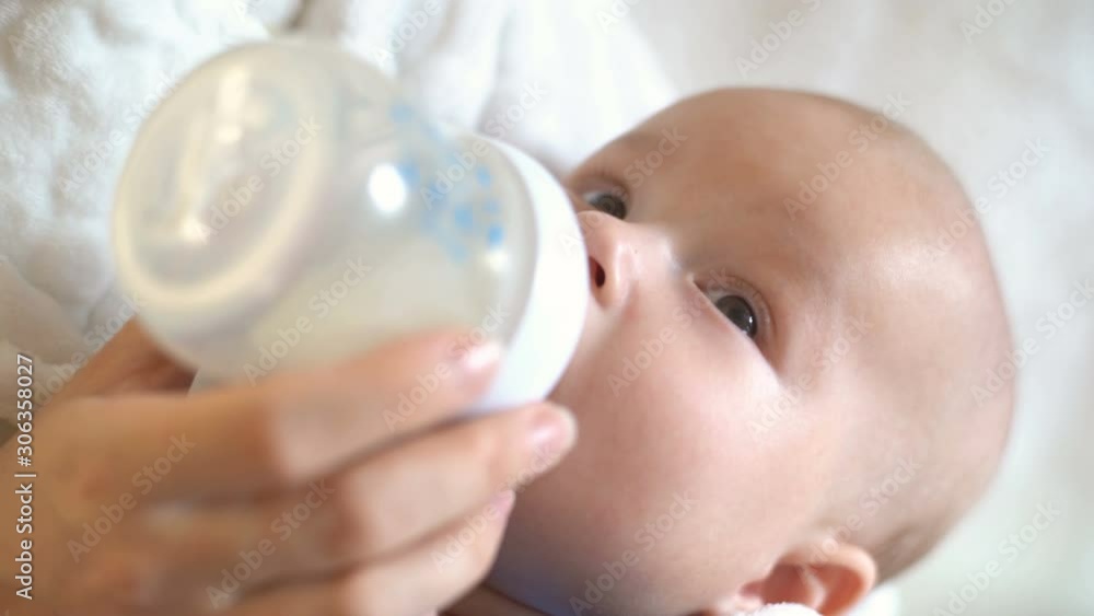 Mother feeds the baby from a bottle with a pacifier. Close-up of a baby. Mother feeds the baby from a bottle with a pacifier. Close-up of a baby.