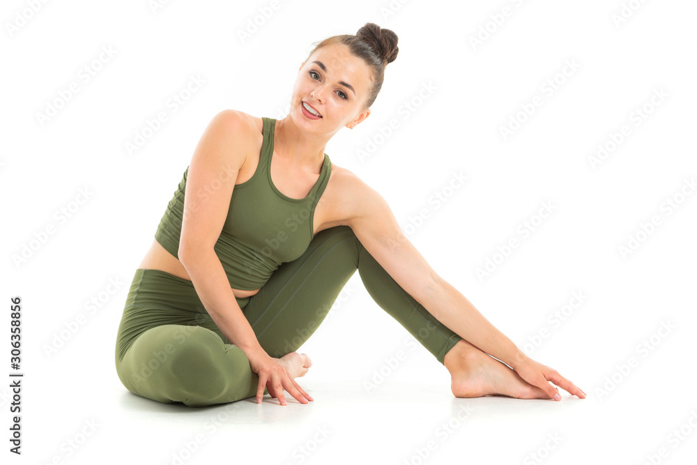 European brunette girl in a green sports suit does yoga on a white background European brunette girl in a green sports suit does yoga on a white background