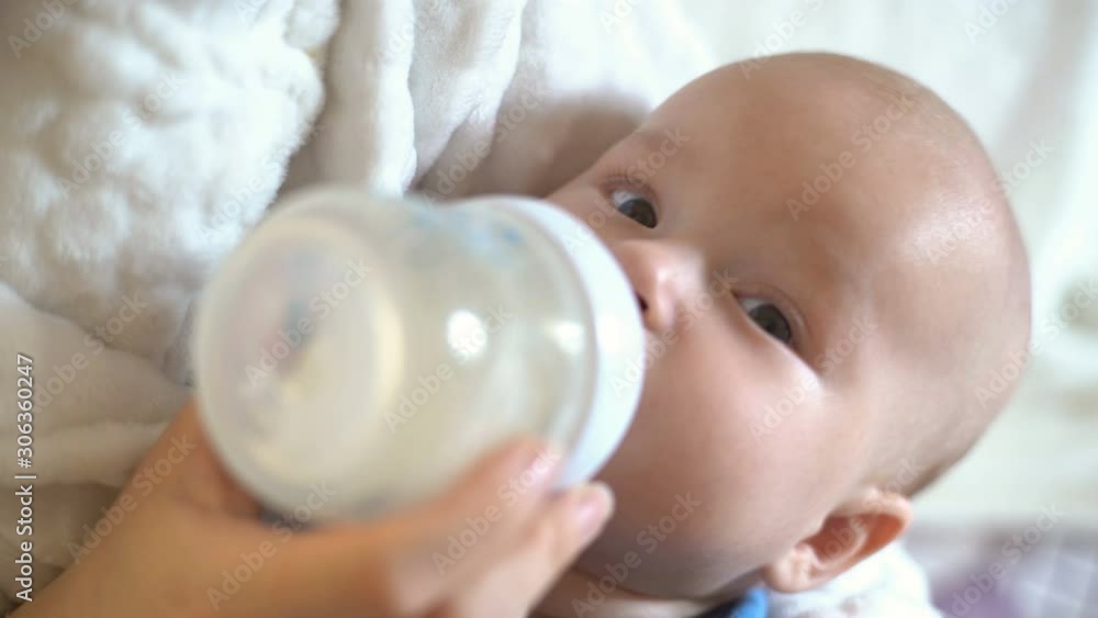 Mother feeds the baby from a bottle with a pacifier. Close-up of a baby. Mother feeds the baby from a bottle with a pacifier. Close-up of a baby.