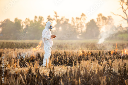 Scientist dosimetrist (radiation supervisor) in protective clothing and gas mask with geiger counter checks the level of pollution