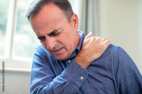 Mature Man Suffering With Trapped Nerve In Shoulder At Home photo