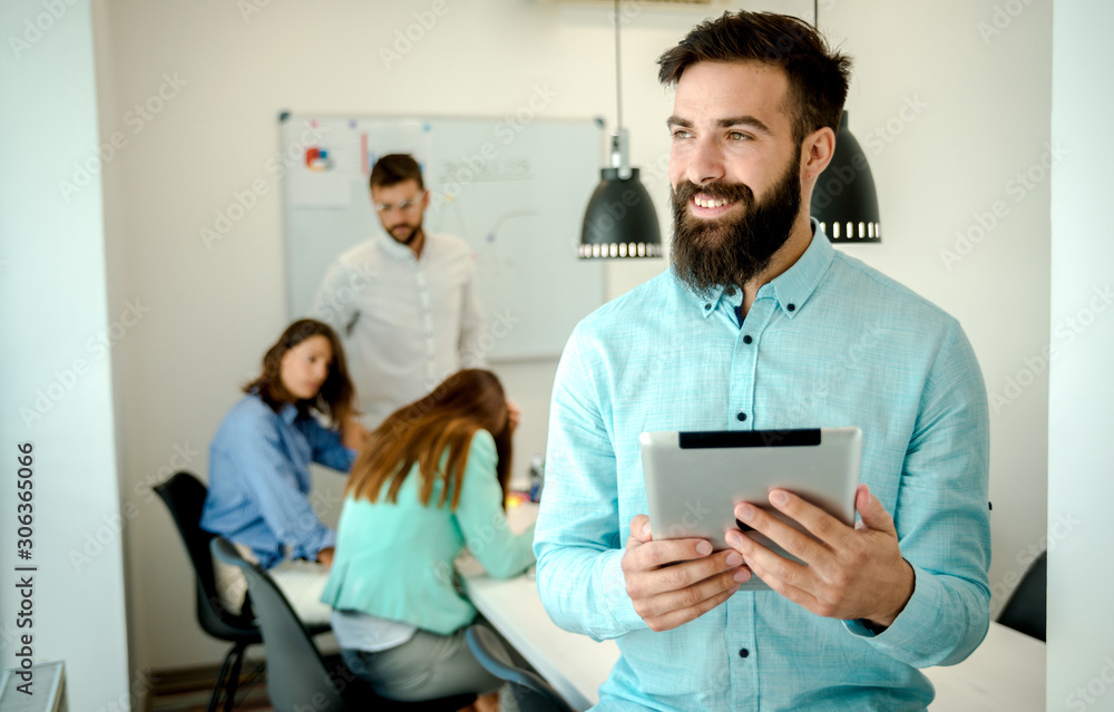 Young man using tablet. In modern office team people work on new project Young man using tablet. In modern office team people work on new project