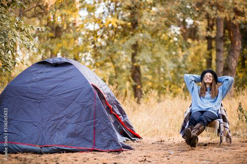 camping holiday, tourist traveler woman in sweater and black hat ralaxing in camp tent in forest, lonely hiker woman enjoy nature trip, rest vacation concept