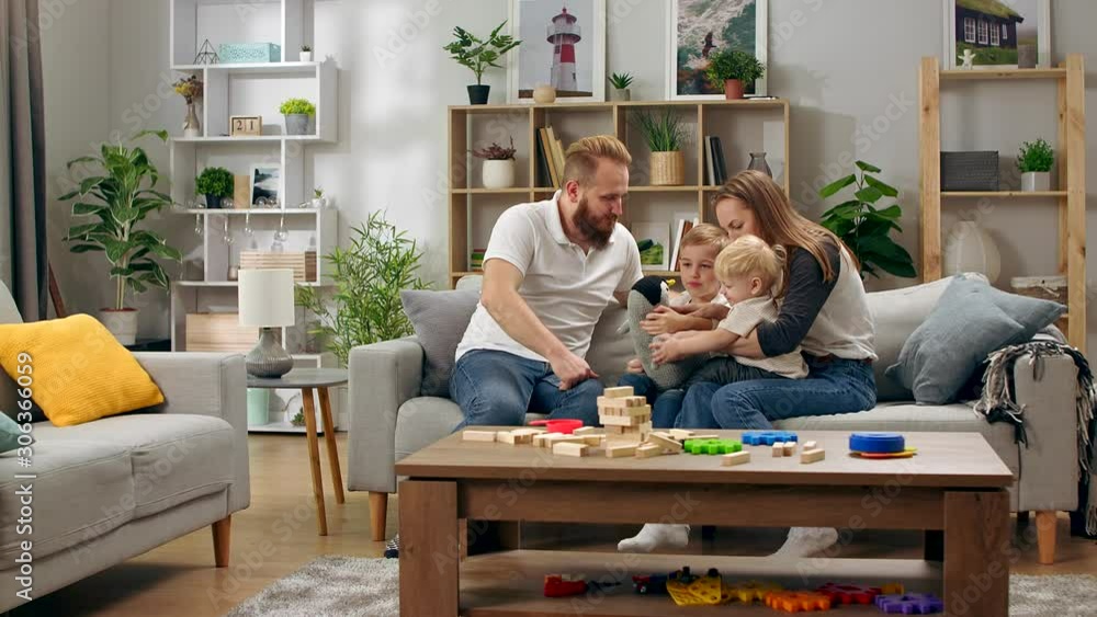 Happy family plays with a toy penguin sitting on a sofa in the living room Happy family plays with a toy penguin sitting on a sofa in the living room