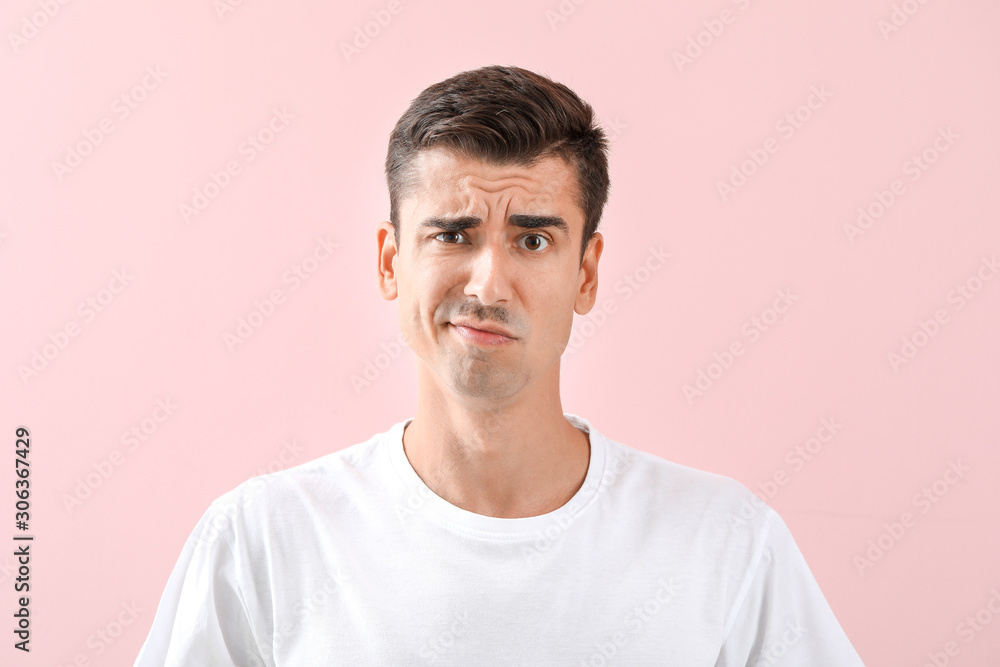 Fototapeta premium Displeased young shaved man on color background