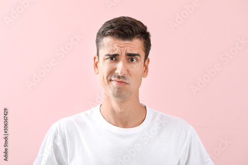 Displeased young shaved man on color background