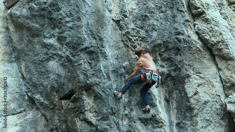back view strong muscular man rock climber climbing on sport route outdoors on a vertical cliff, making hard wide move and gripping hold. 120 fps slow motion back view strong muscular man rock climber climbing on sport route outdoors on a vertical cliff, making hard wide move and gripping hold. 120 fps slow motion