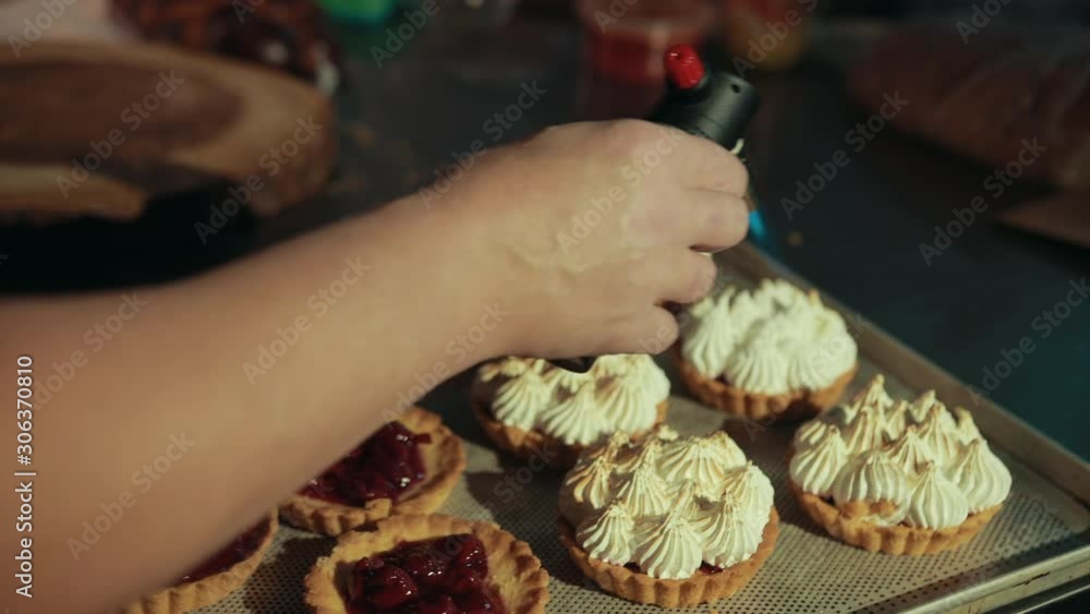 Process of decorating tarts with pastry burner, making cream brown. Confectioner is using device to decorate, change color of traditional French dessert. Process of decorating tarts with pastry burner, making cream brown. Confectioner is using device to decorate, change color of traditional French dessert.