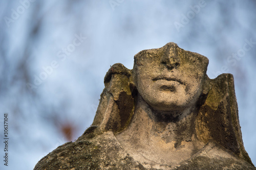 Monument and candles in the cemetery. All Saints Day in Poland. Stone statue. Statue without a face.