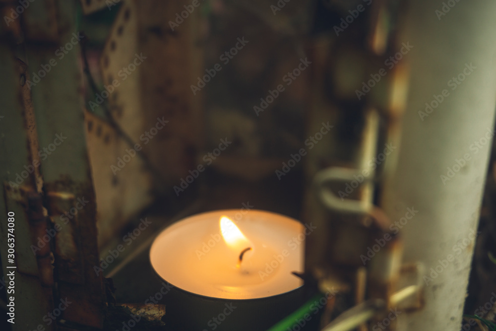 Closeup of a burning tealight in a rusted and weathered lantern