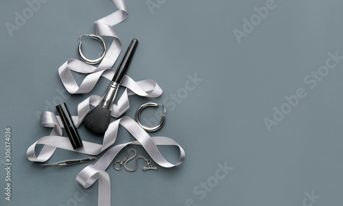 Beautiful Christmas tree made of makeup supplies, jewelry and ribbon on grey background