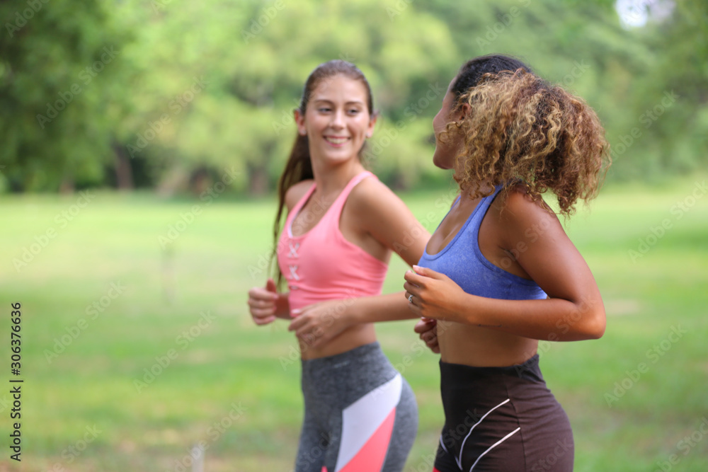 Healthy beautiful sportswoman wearing tracksuit jogging in the park, African american women and Caucasian women Healthy beautiful sportswoman wearing tracksuit jogging in the park, African american women and Caucasian women