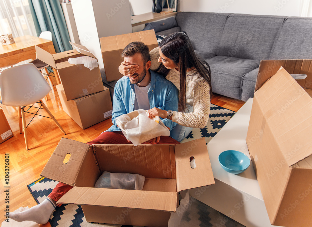 Smiling young couple move into a new home sitting on floor and unpacking. Smiling young couple move into a new home sitting on floor and unpacking.