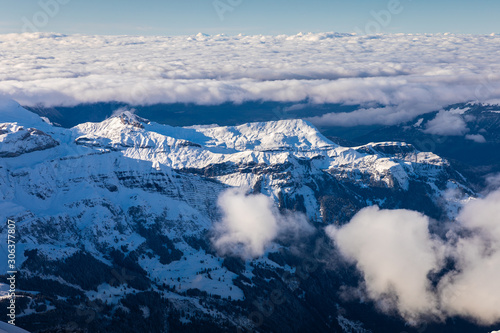 Aerial of snowcapped mountain range on cloudy day.