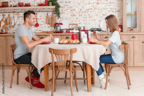 Happy young couple having breakfast on Christmas eve
