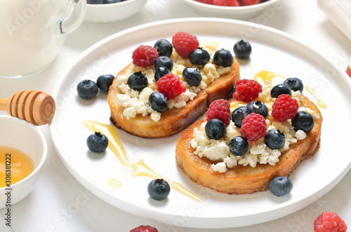 Sandwiches with blueberries, raspberries and honey on toasts with curd cheese
