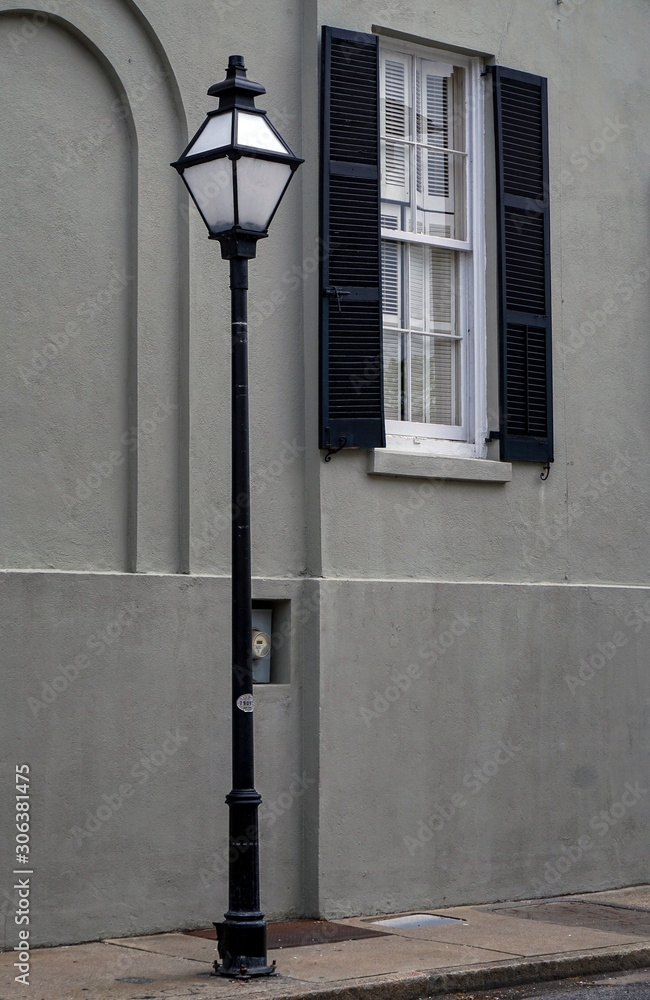 Black wrought iron street lamp post and black wrought iron shutters adorn a window