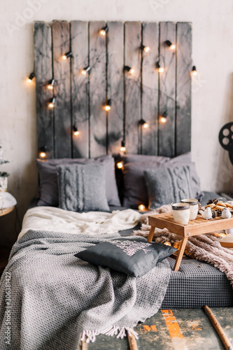 Cozy room with table, a cup on the bed, marshmallow and cookies, cozy knitted blanket. New Year 2020, flat lay. Christmas composition with a mug, tray, a deer and a Christmas tree.