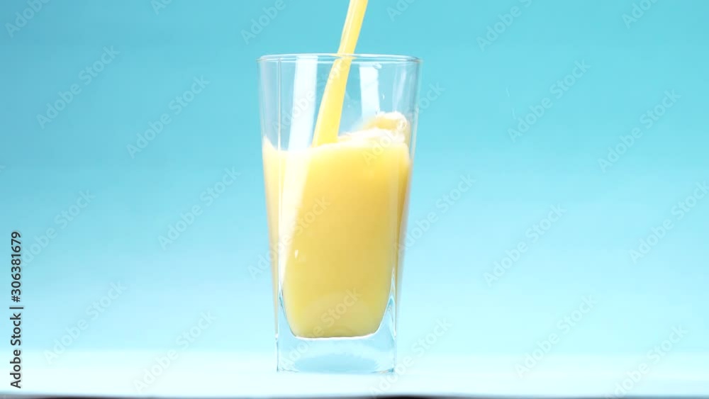 orange juice is poured into a glass on blue background orange juice is poured into a glass on blue background