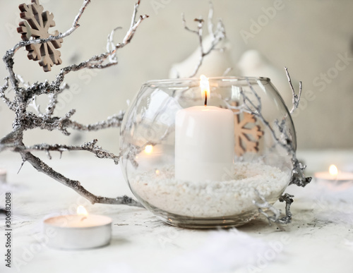 Glowing candles with Christmas decor on white background photo