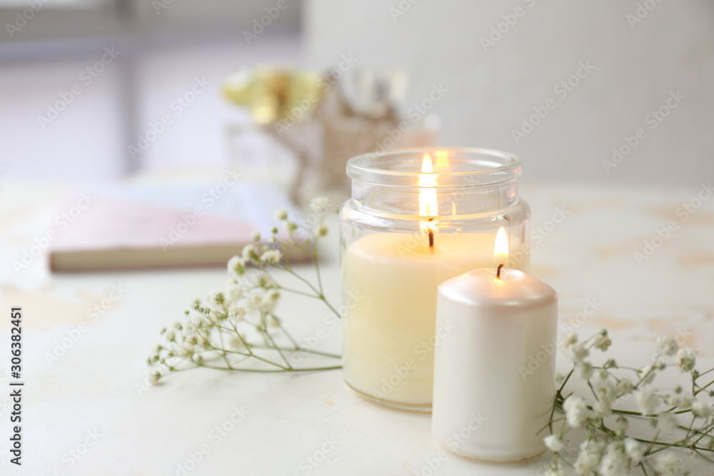Glowing candles with flowers on white table