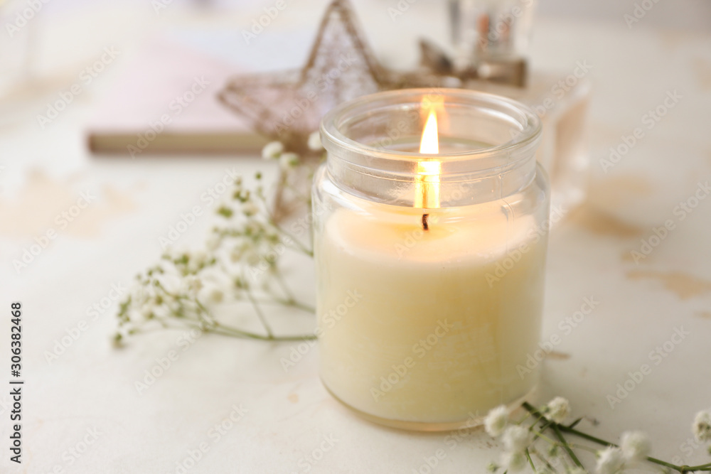 Glowing candle with flowers on white table Glowing candle with flowers on white table