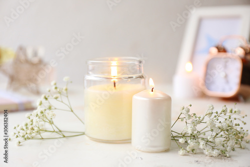 Glowing candles with flowers on white table photo