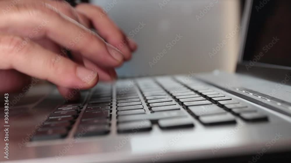 closeup of man's hands as he writes on the keyboard of a laptop