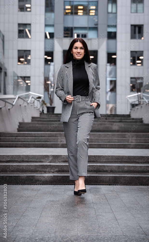 Full length portrait of beautiful woman in stylish suit on city street