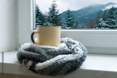 green circle in the scarf, the window with maple leaves and drops after rain in autumn season when you need warm drinks