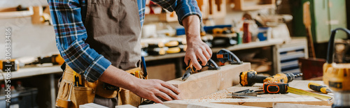 Quadro su tela panoramic shot of carpenter holding pliers near wooden dowel