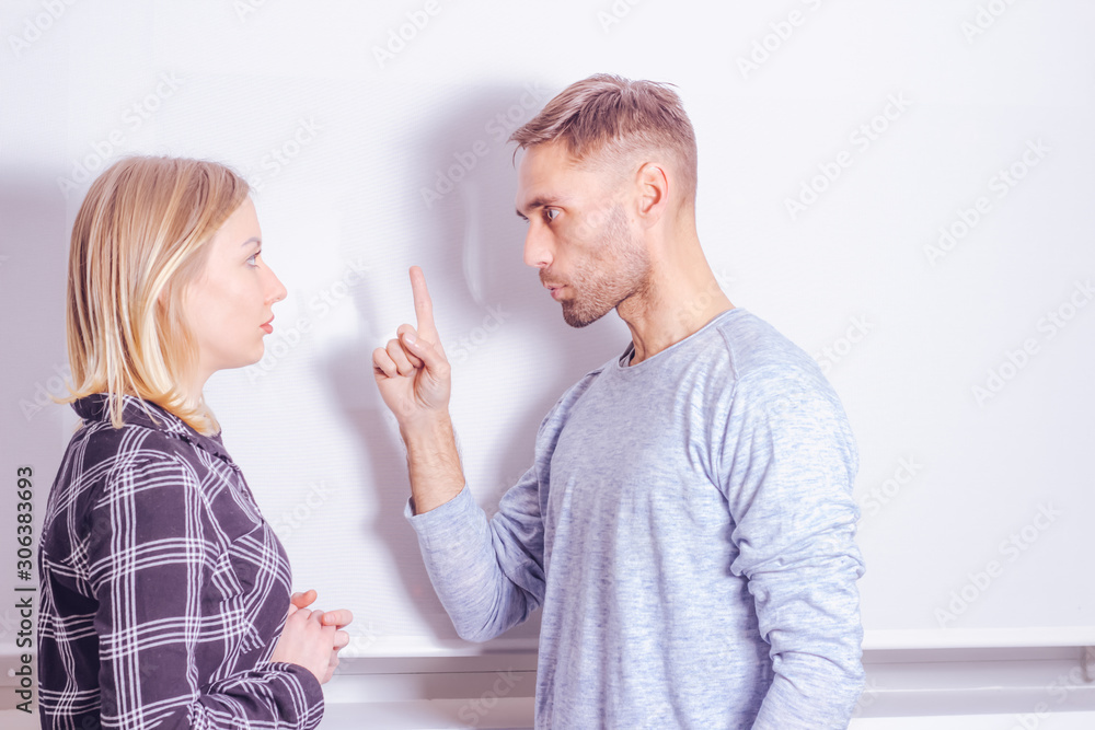 Violent argument of couple concept. Young man warns his wife with threatening gesture Violent argument of couple concept. Young man warns his wife with threatening gesture