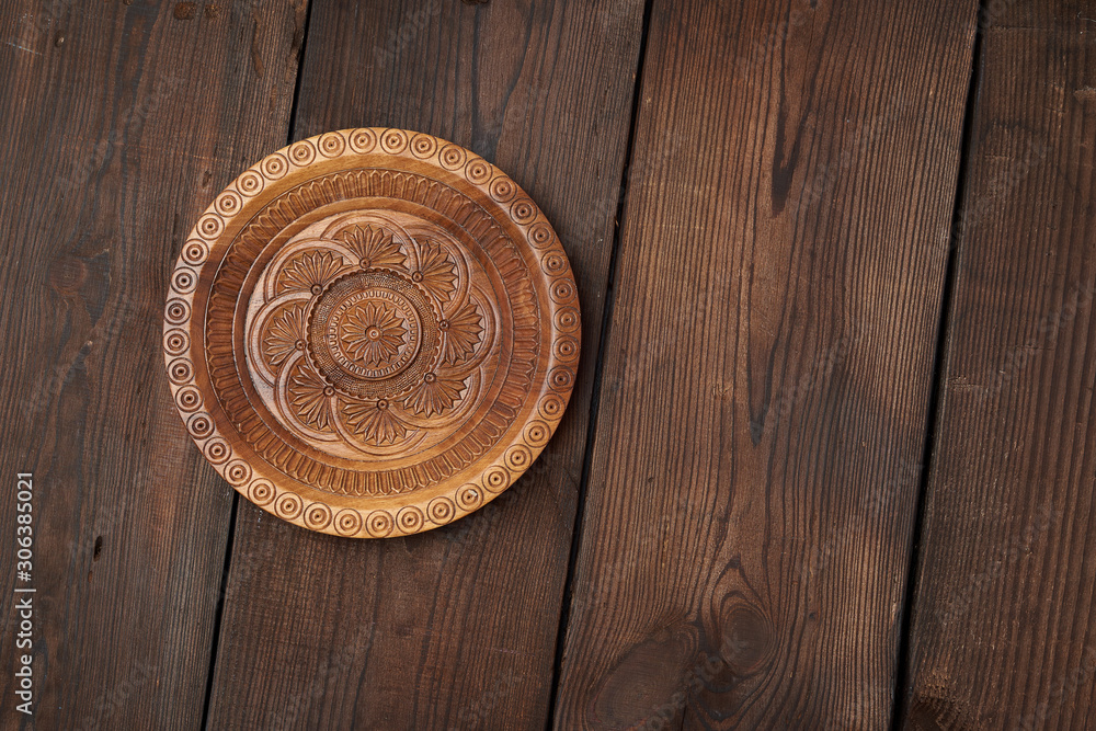 empty round brown carved decorative plate standing on a wooden background