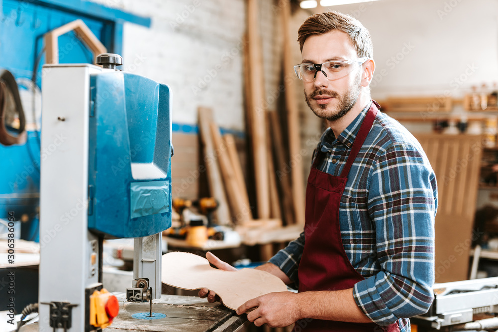 handsome carpenter holding wooden chopping board in workshop handsome carpenter holding wooden chopping board in workshop