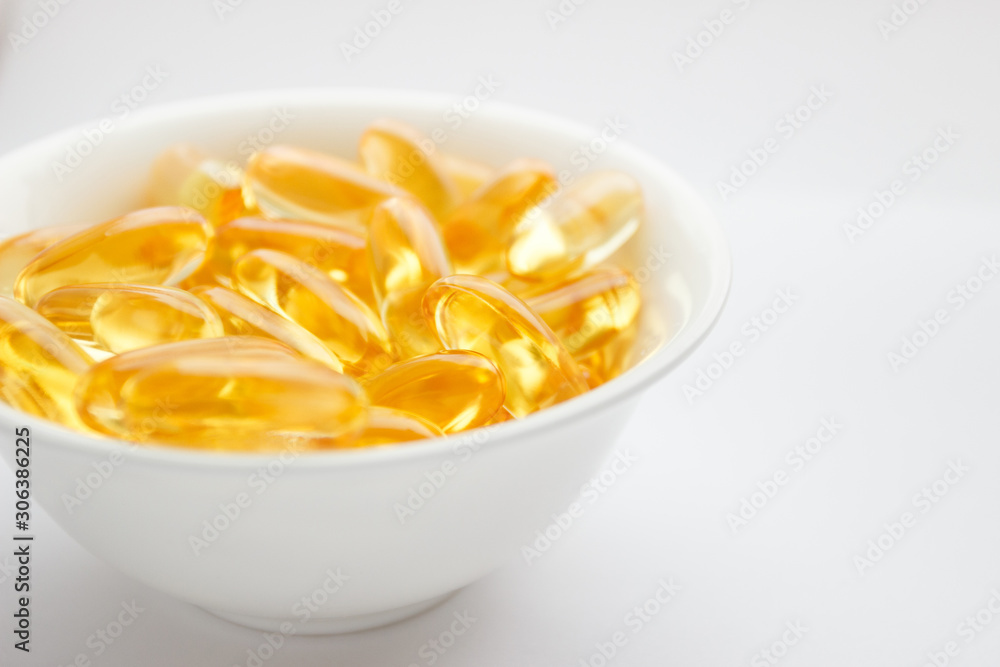 Dietary supplementation. Capsules of fish oil in the white bowl, light background Dietary supplementation. Capsules of fish oil in the white bowl, light background