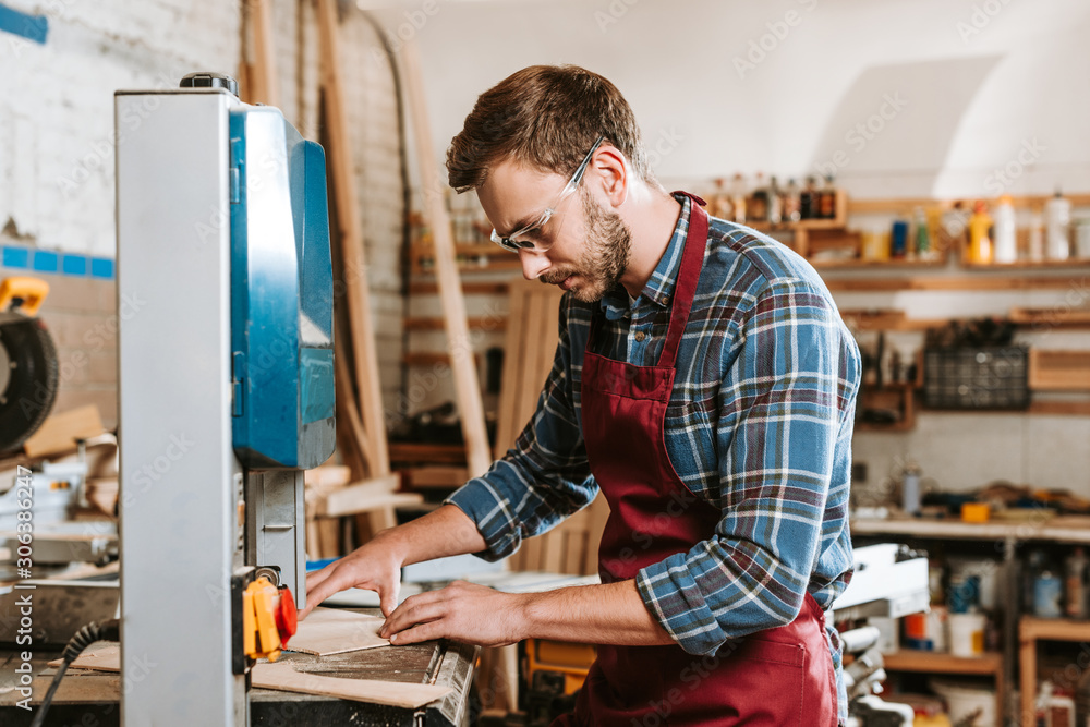 selective focus of carpenter in safety glasses and apron using cnc machine selective focus of carpenter in safety glasses and apron using cnc machine