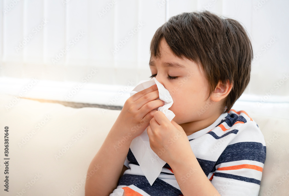 Unhealthy kid blowing nose into tissue, Child suffering from running nose or sneezing , A boy catches a cold when season change, childhood wiping nose with tissue Unhealthy kid blowing nose into tissue, Child suffering from running nose or sneezing , A boy catches a cold when season change, childhood wiping nose with tissue