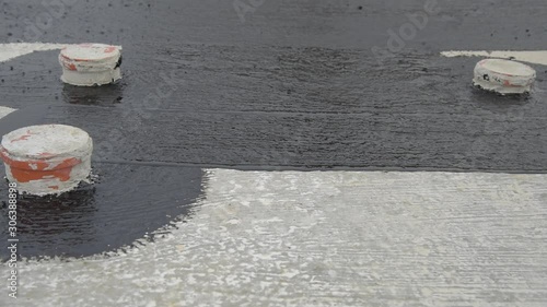 Waterproofing coating. Worker applies bitumen mastic on the foundation. Roofer cover the rooftop polymer modified bitumen waterproofing primer, with a roller brush.