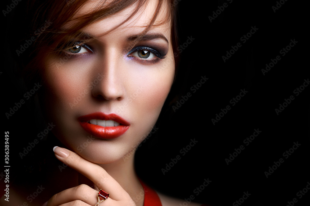 Fototapeta premium Close-up beautiful girl with bright evening party or prom make-up red lipstick isolated on a dark background