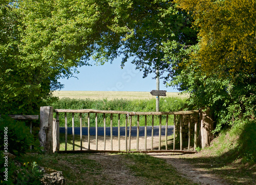 gate at the exit of the Park on the road  pointer and view of the field and the blue sky