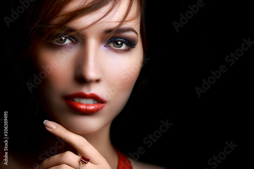 Close-up beautiful girl with bright evening party or prom make-up red lipstick isolated on a dark background