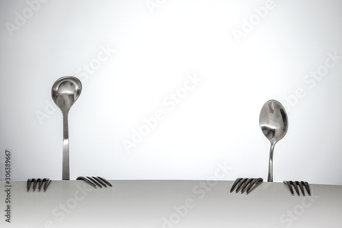 conceptual photography. Improvised stage. Image of a two people from spoon and forks, sitting at a table. Theme of food and restaurant business