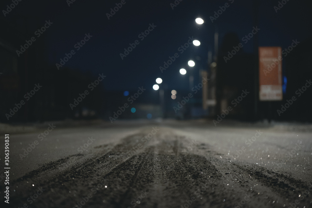 Empty snowy winter road at night time background. Blurred image.