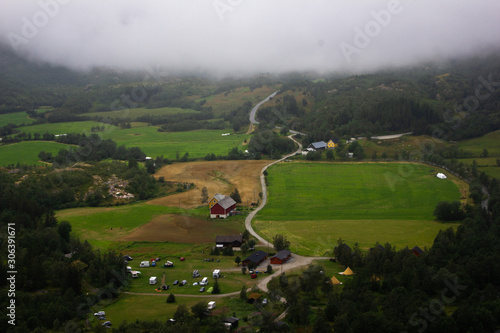 View of a Norwegian farm from a very dangerous serpentine. Around the green fields, forest.