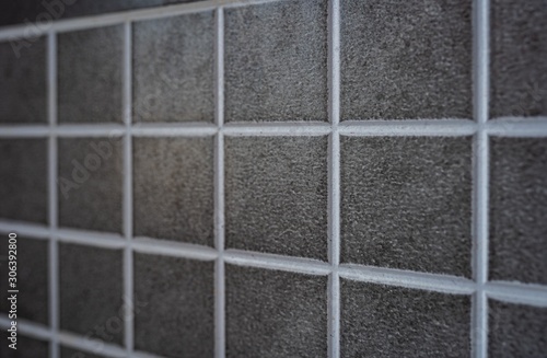 Interior wall of grey tiles background texture. Wallpaper pattern of small squares.