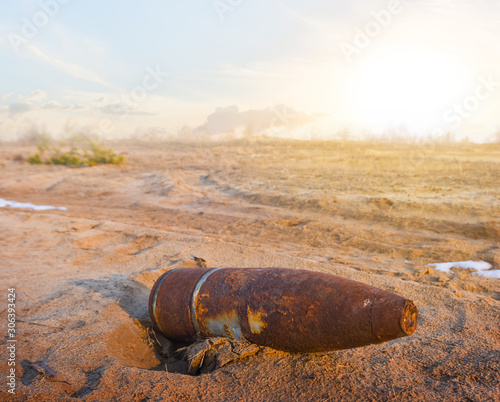 old rusty bomb  lie on a sand afrer a fairing at the sunset photo