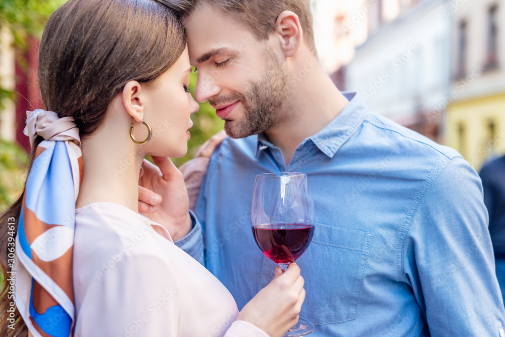 handsome boyfriend touching face of beautiful girlfriend holding glass of red wine handsome boyfriend touching face of beautiful girlfriend holding glass of red wine