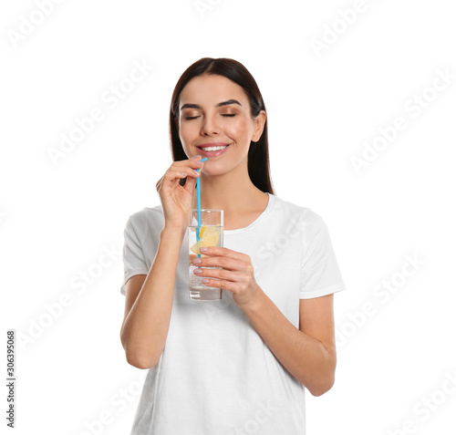 Beautiful young woman drinking tasty lemon water on white background